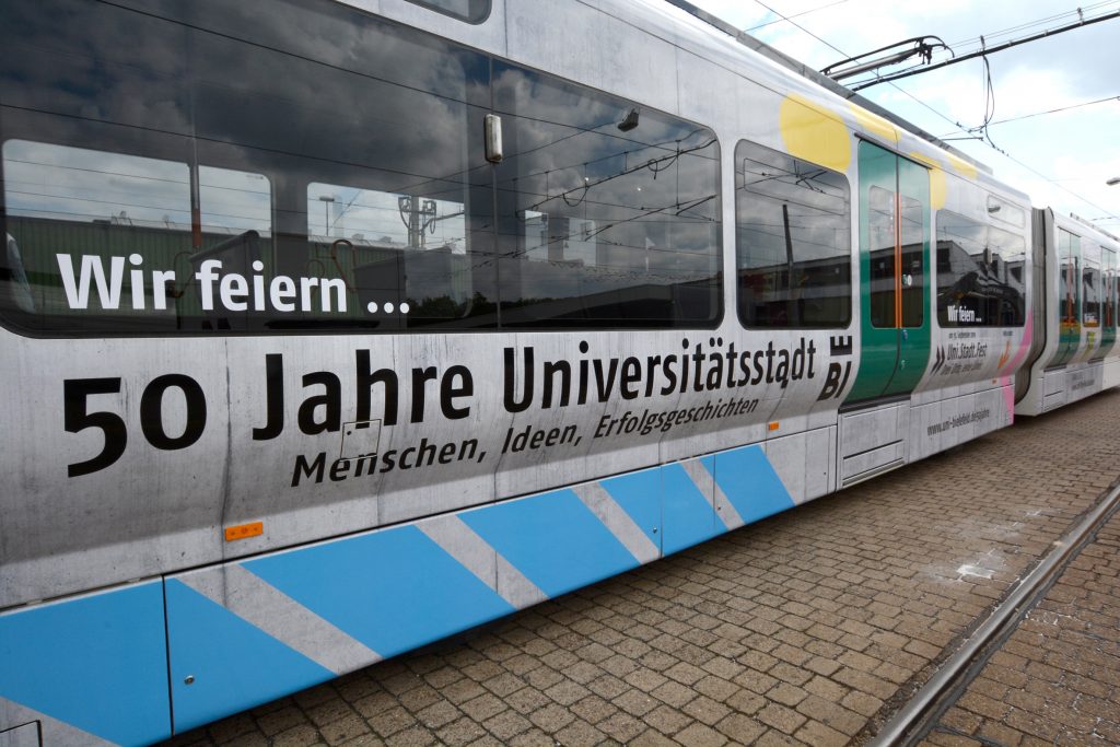 Die mit Jubiläumsmotiven beklebte Vamosbahn trägt das Universitätsjubiläum in die Stadt. Foto: Universität Bielefeld