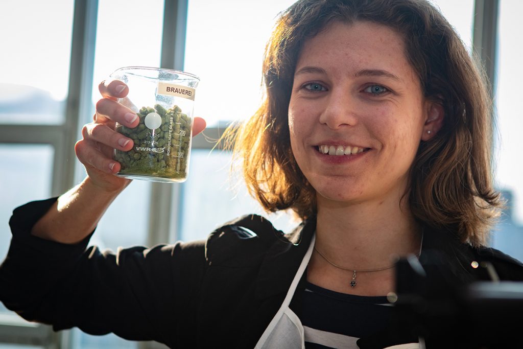 Für das Jubiläums-Bier benutzt die Campusbrauerei Hopfen mit Citrus-Noten, wie sie Luisa Blöbaum zeigt. Foto: Universität Bielefeld / Mike-Dennis Müller